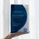 Amazing You Epsom Salts Detox Bath Soak Pure Magnesium Sulphate 1kg lifestyle shot of a hand holding the blue pouch in front of a white curtain