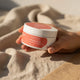Amazing You Fix My Face Magnesium Moisturiser 100g lifestyle shot of a hand holding the tub on soft sand coloured fabric, close up of the tub