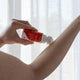 Amazing You Magnesium Joint Gel 60ml lifestyle shot of a hand rolling the bottle onto an arm in front of a white curtain, styled lifestyle photo