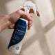 Amazing You Magnesium Sensitive Spray 200ml lifestyle shot of a hand holding the navy and white spray bottle against a beige wall