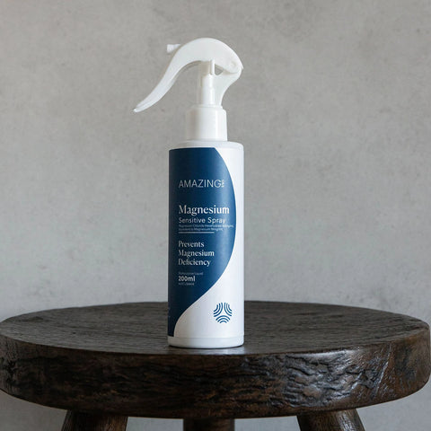 Amazing You Magnesium Sensitive Spray 200ml lifestyle shot of the spray bottle standing on a dark wooden stool against a grey wall