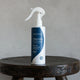 Amazing You Magnesium Sensitive Spray 200ml lifestyle shot of the spray bottle standing on a dark wooden stool against a grey wall