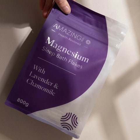 Amazing You Magnesium Sleep Bath Flakes 800g lifestyle shot of a hand holding the purple pouch tilted towards the camera, styled lifestyle photo