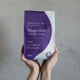 Amazing You Magnesium Sleep Bath Flakes 800g lifestyle shot of two hands holding up the purple pouch against a grey wall, styled lifestyle photo