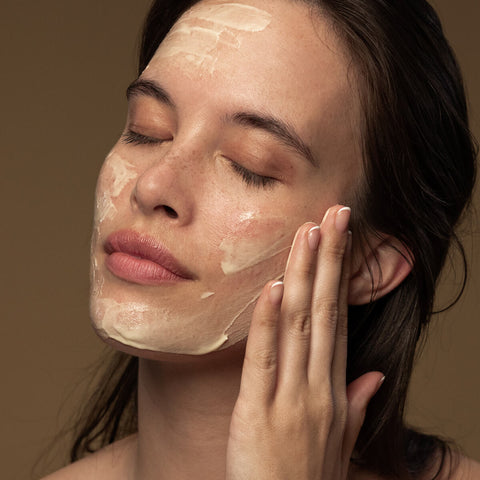 Woman applying antipodes aura manuka honey mask to her face.