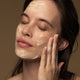 Woman applying antipodes aura manuka honey mask to her face.