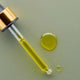 Gold dropper with greenish yellow rosehip & avocado oil face oil.