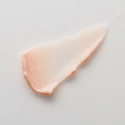 Close-up of a pinkish-beige smear of flora probiotic skin rescue hyaluronic mask on a light grey background.
