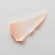 Close-up of a pinkish-beige smear of flora probiotic skin rescue hyaluronic mask on a light grey background.