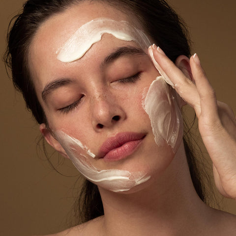 Model applying antipodes grace gentle cream cleanser to her face.