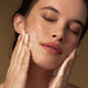 Model applying anti-blemish gel cleanser to her cheeks.