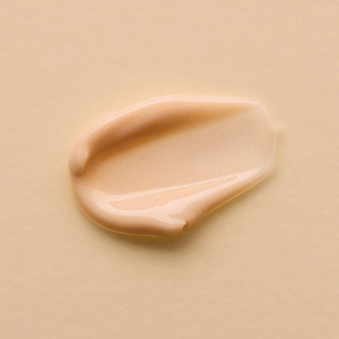 Swatch of smooth & creamy kiwi seed gold luminous eye cream on a pale peach background.