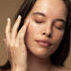 Model applying kiwi seed oil eye cream to her under eye area.