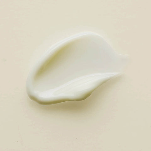 Swatch of Kiwi Seed Oil Eye Cream with smooth and creamy texture and a pale white shade on a cream background.