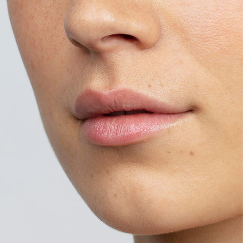 Antipodes kiwi seed oil lip conditioner on a person's lips.