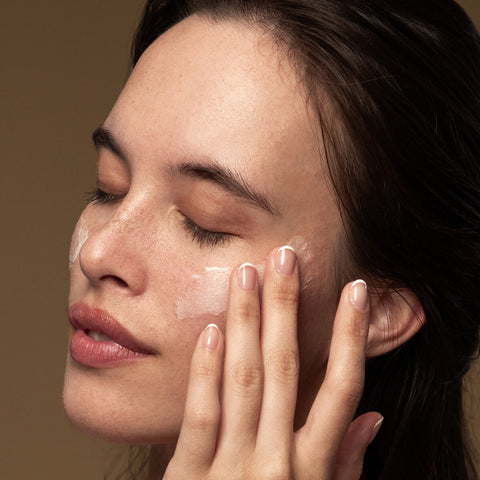 Model applying lime caviar collagen rich firming cream to her cheek.