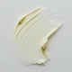 Swatch of lime caviar collagen rich firming cream, with a smooth and thick texture on a grey background.
