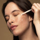 Model applying maya serum to her cheek with dropper applicator.