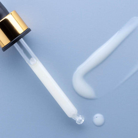 Dropper applicator with a swatch of maya serum on a baby blue background.