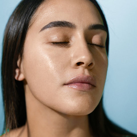 Model wearing supernatural spf50 ceramide silk sunscreen on her face, with a glowing complexion and lit by the sun.