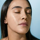 Model wearing supernatural spf50 ceramide silk sunscreen on her face, with a glowing complexion and lit by the sun.