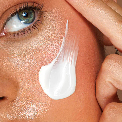 Close-up of a hand applying sunscreen to a person's skin.