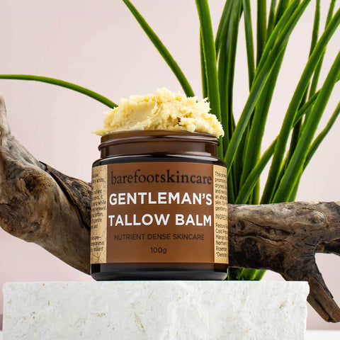 Jar of 'Gentleman's Tallow Balm' by barefootskincare with a plant and wooden branch in the background.