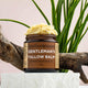 Jar of 'Gentleman's Tallow Balm' by barefootskincare with a plant and wooden branch in the background.