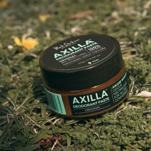 Black Chicken Remedies Axilla Deodorant Paste Original 75g tin sitting on green grass and moss, outdoor lifestyle shot of the closed tin