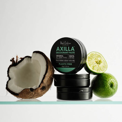Black Chicken Remedies Axilla Deodorant Paste Original Plastic Free 60g stack of black tins beside half a coconut and limes, styled shot