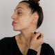 Black Chicken Remedies Essential Oil Perfume #1 Transcendence lifestyle shot of a woman with her hair up, in profile, rolling the perfume on her neck