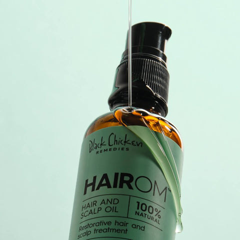 Black Chicken Remedies HairOM Hair & Scalp Oil 50ml lifestyle close up of the bottle against a mint backdrop, looking up at the pump