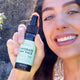 Black Chicken Remedies Hydrate My Face Toning Mist lifestyle shot of a smiling woman holding up the bottle, styled lifestyle photo