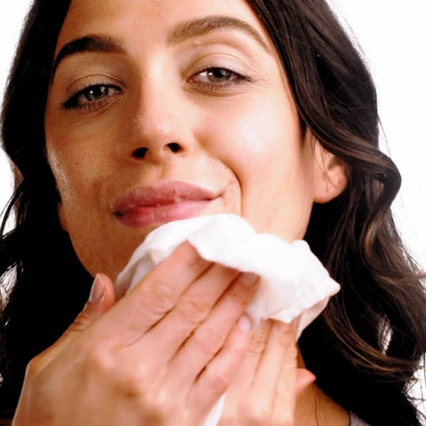 Black Chicken Remedies Muslin Face Cloth Pack lifestyle shot of a woman with dark wavy hair wiping her face with a white muslin cloth