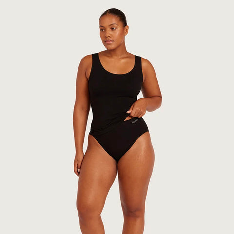 A woman modeling a black one-piece swimsuit against a light gray studio background. The brand name 'BOODY' is visible in small white text on the front left hip of the swimsuit.