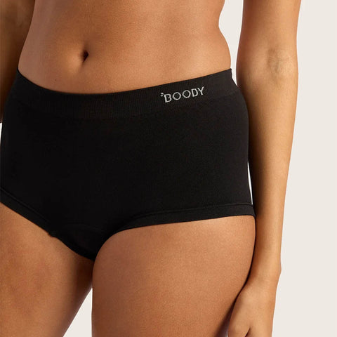A close-up of a model wearing black high-waisted briefs with the brand name 'BOODY' printed in white on the front waistband, set against a light gray studio background.