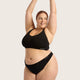 Boody G-String Black lifestyle shot of a smiling woman with her arms raised in a black bra top and the black g-string, styled lifestyle photo