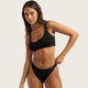 Boody G-String Black lifestyle shot of a woman with long dark hair in a black bra top and the black g-string, front view, styled lifestyle photo