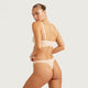 Boody G-String Shell lifestyle back view of a woman looking over her shoulder in a nude bra and nude g-string, styled lifestyle photo