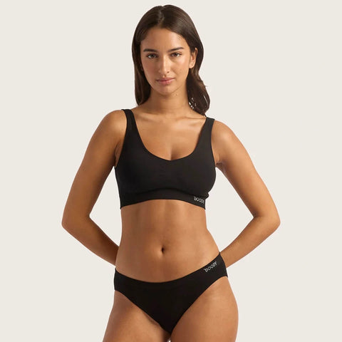 Boody Hipster Bikini Black lifestyle shot of a woman standing in a black crop top and black bikini briefs, front view, plain backdrop