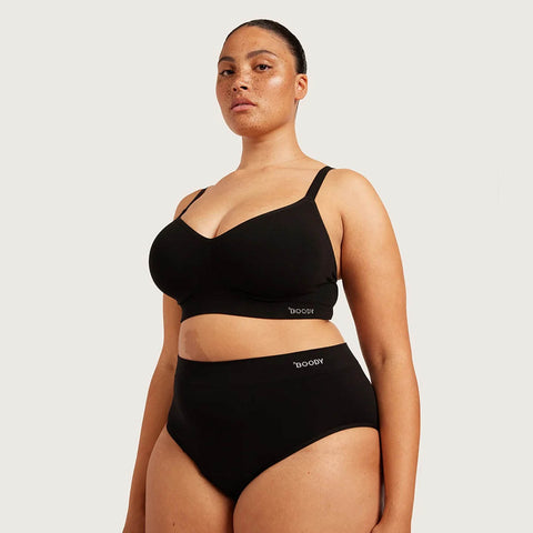 Boody Period & Leak Proof Full Briefs Light-Moderate lifestyle shot of a woman with a hand on her hip in a black bra and the black full briefs