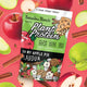 Botanika Blends Plant Protein Oh My Apple Pie lifestyle shot of the pouch among red and green apples and cinnamon sticks on a pink backdrop