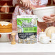 Botanika Blends Plant Protein Vanilla Cake Batter 500g lifestyle shot of the pouch on a kitchen bench with baking bowls and a cake behind