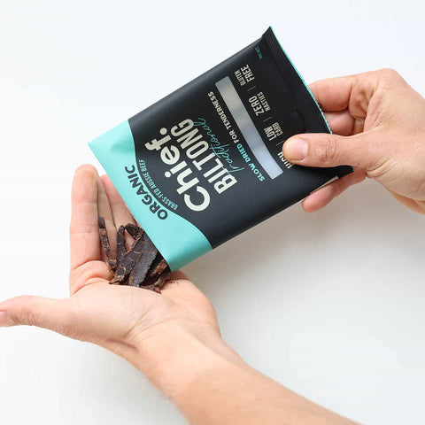 Person holding a package of biltong with a white background