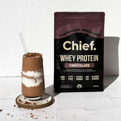 Chocolate protein shake with a package of Chief Whey Protein Chocolate on a white background