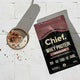 Chief Whey Protein package on a white tiled surface with a glass of chocolate smoothie.