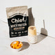 Unflavoured whey protein pictured next to a bowl of diced mango and a smoothie in a glass.