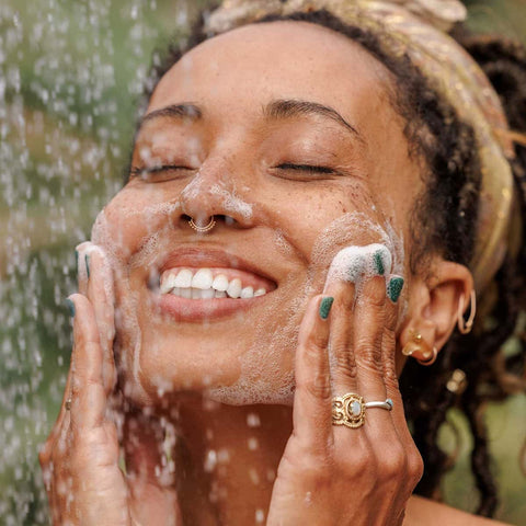 Woman washing her face with water outdoors.