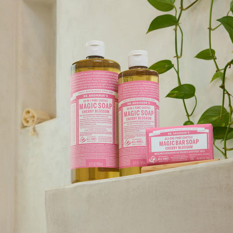Range of Dr Bronners Cherry Blossom Magic Soaps on a stone surface with vines in the background.