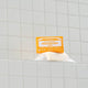 Bar of soap with a yellow label on a tiled bathroom shelf